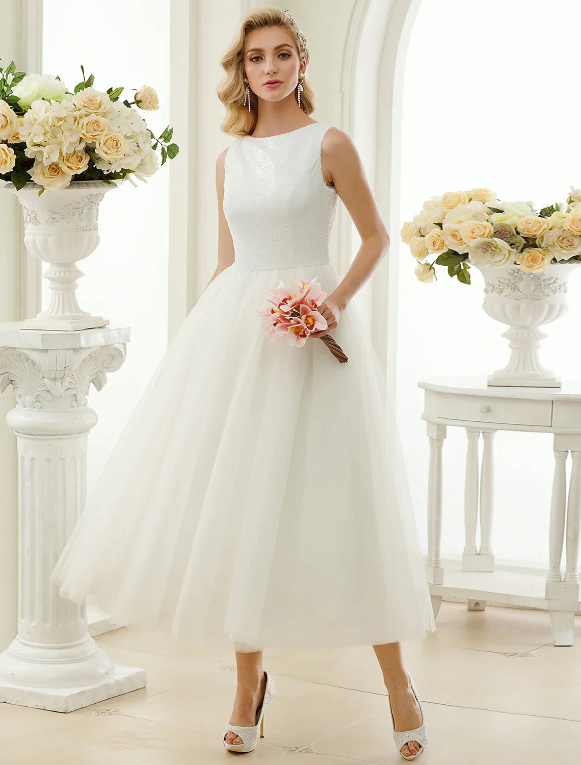 Model wearing a sparkling A-line tea length wedding dress with lace and sequin details.