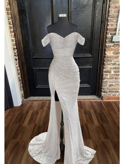 Model wearing a sparkly mermaid trumpet evening gown with a cowl neck and ruched details.