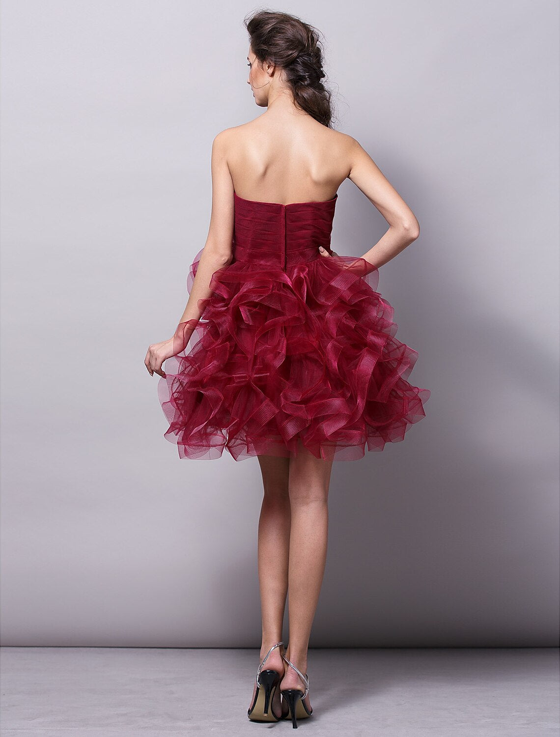 Model smiling in a pink strapless homecoming dress, with a focus on the bodice.